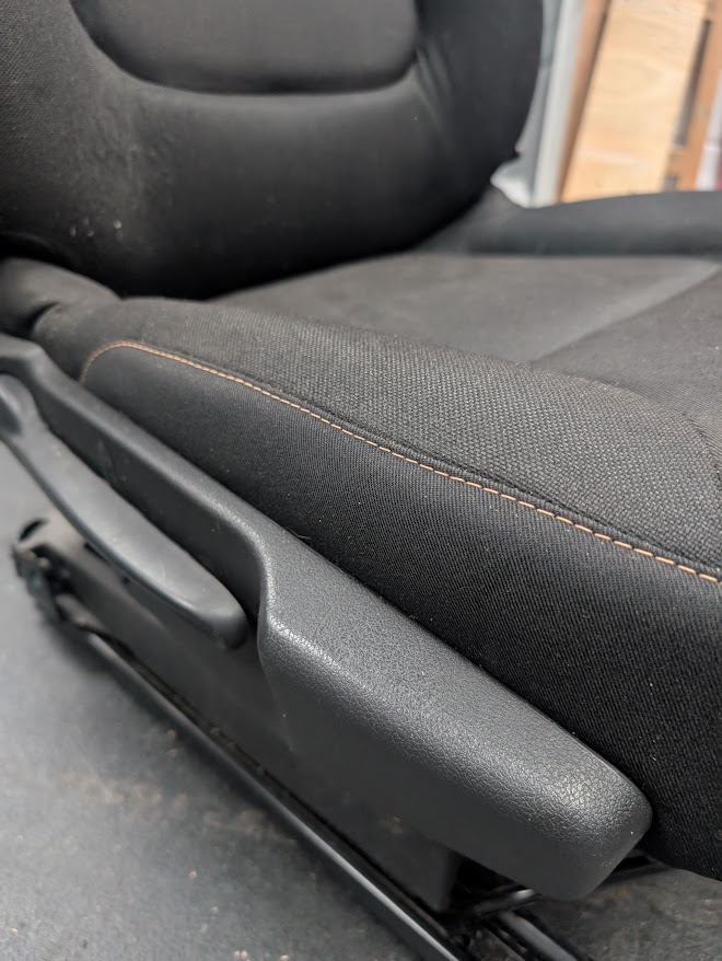 Black cloth vehicle seat after bolster repair with contrast stitching